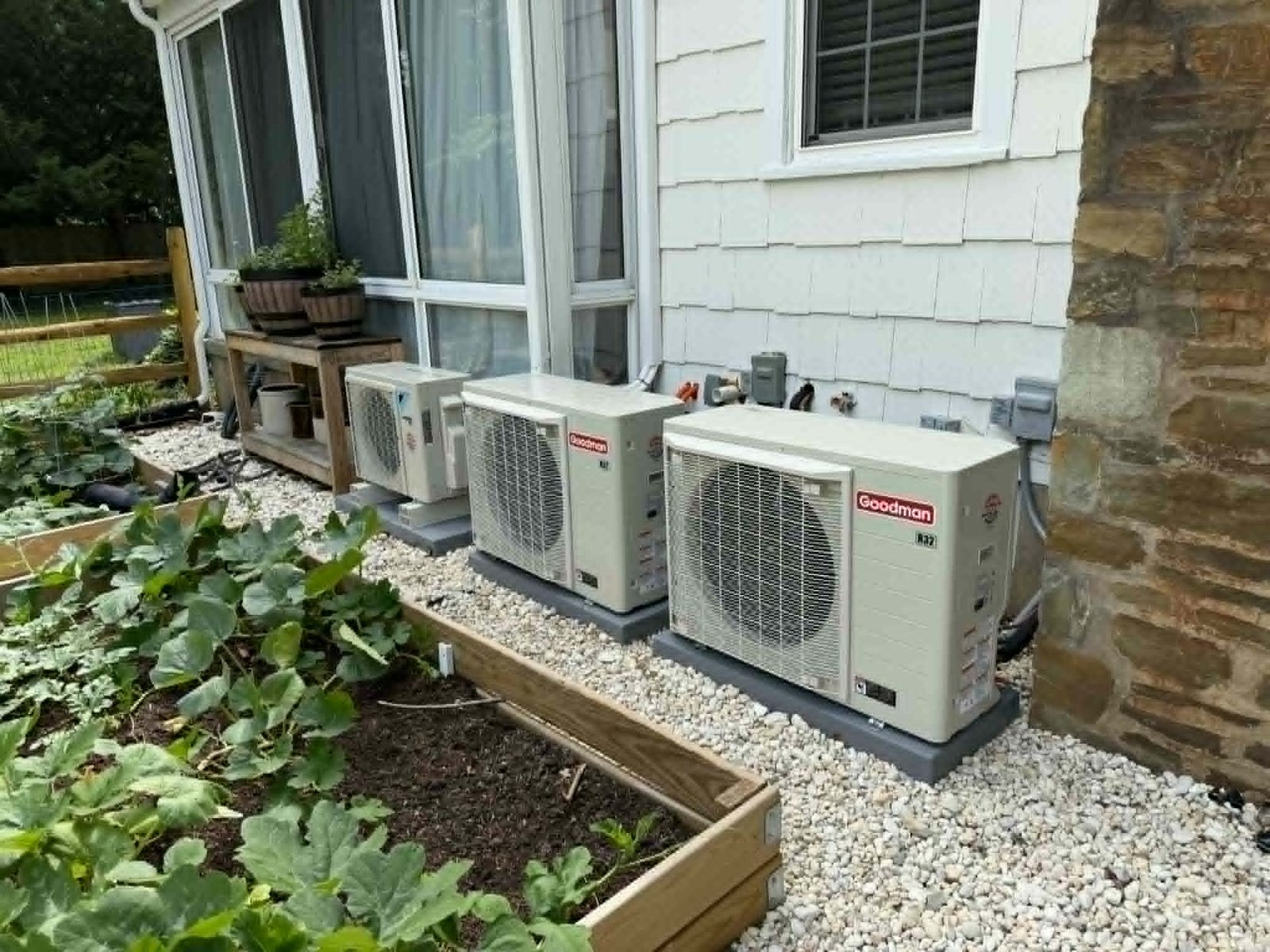 Row of Goodman R-32 side-discharge inverter condensers fit neatly along a home's side wall next to a garden bed